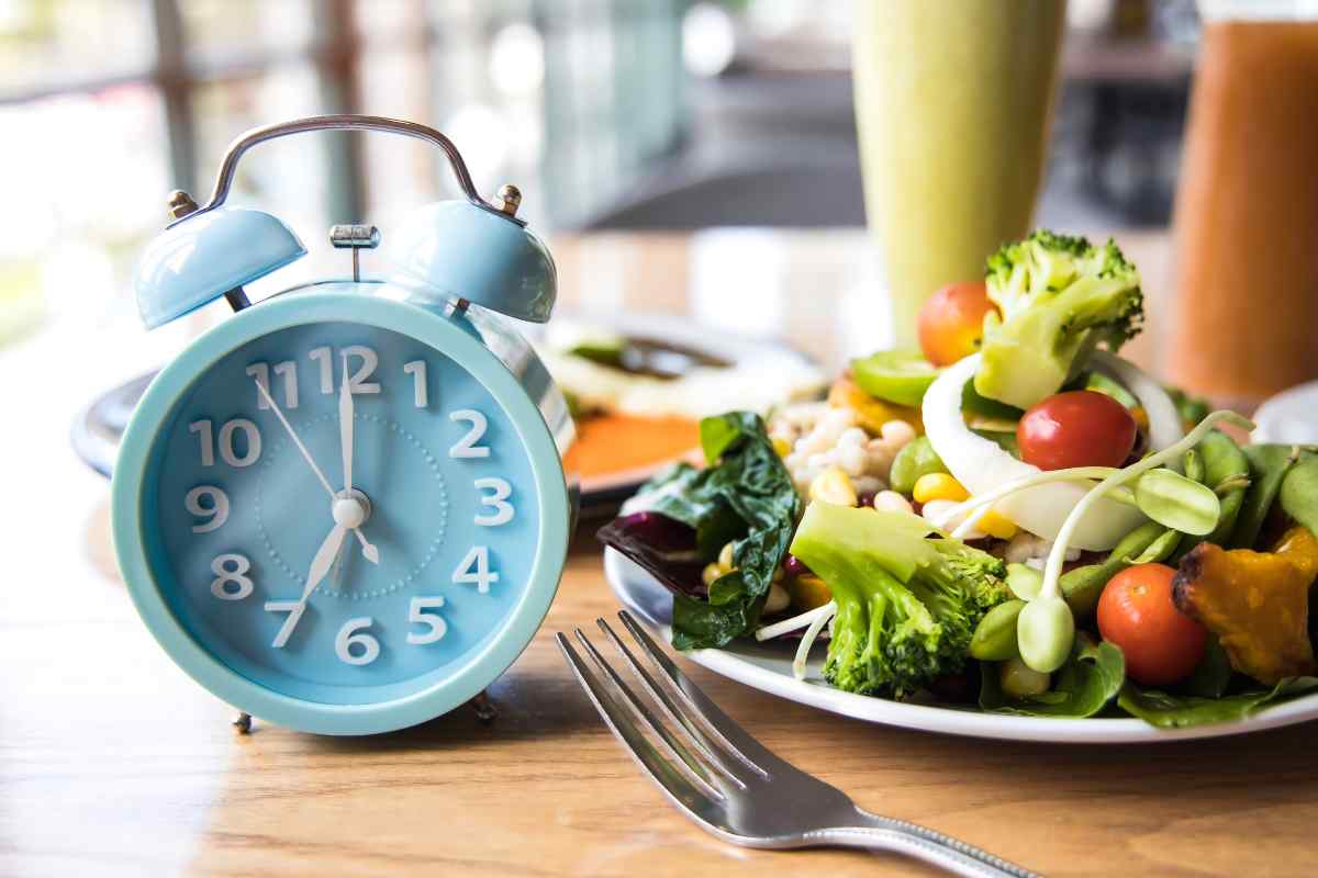 Piatto di insalata vicino a una forchetta e a un orologio